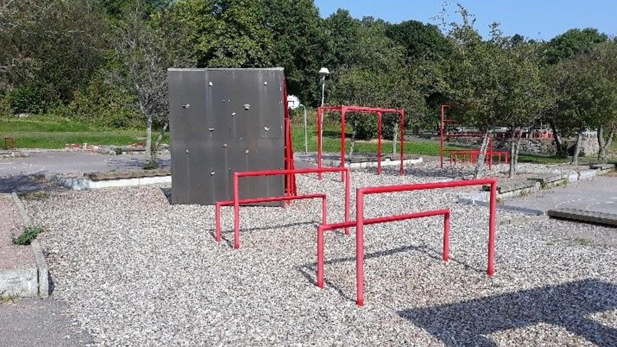 Utegym med hinderbana och redskap i metall på grusunderlag