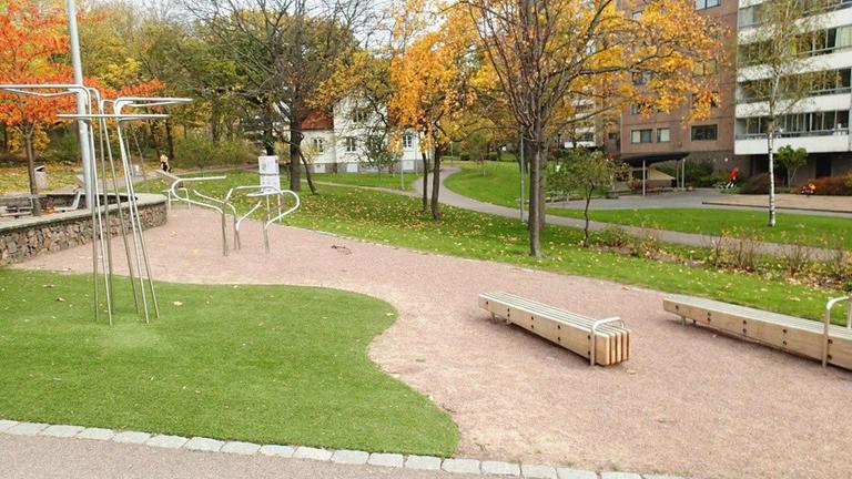 Utegym i trä och metall med grusad gång och gräsmattor