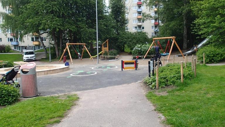Lekplats med gräsmattor, asfaltering, många sittplatser och olika lekytor