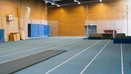 Blå löparbanor med stavhoppsmadrass i bakgrunden. 