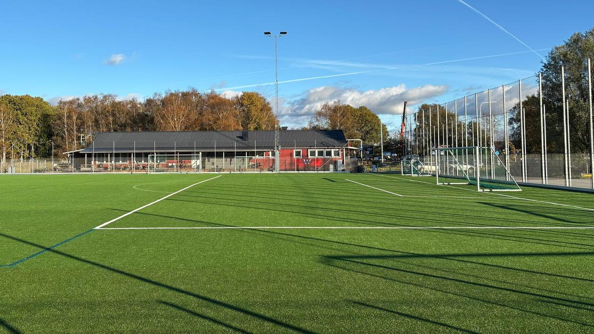 En grön fotbollsplan under blå himmel.