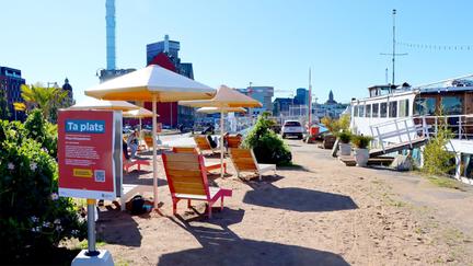 Solstolar och parasoll på sandigt underlag.