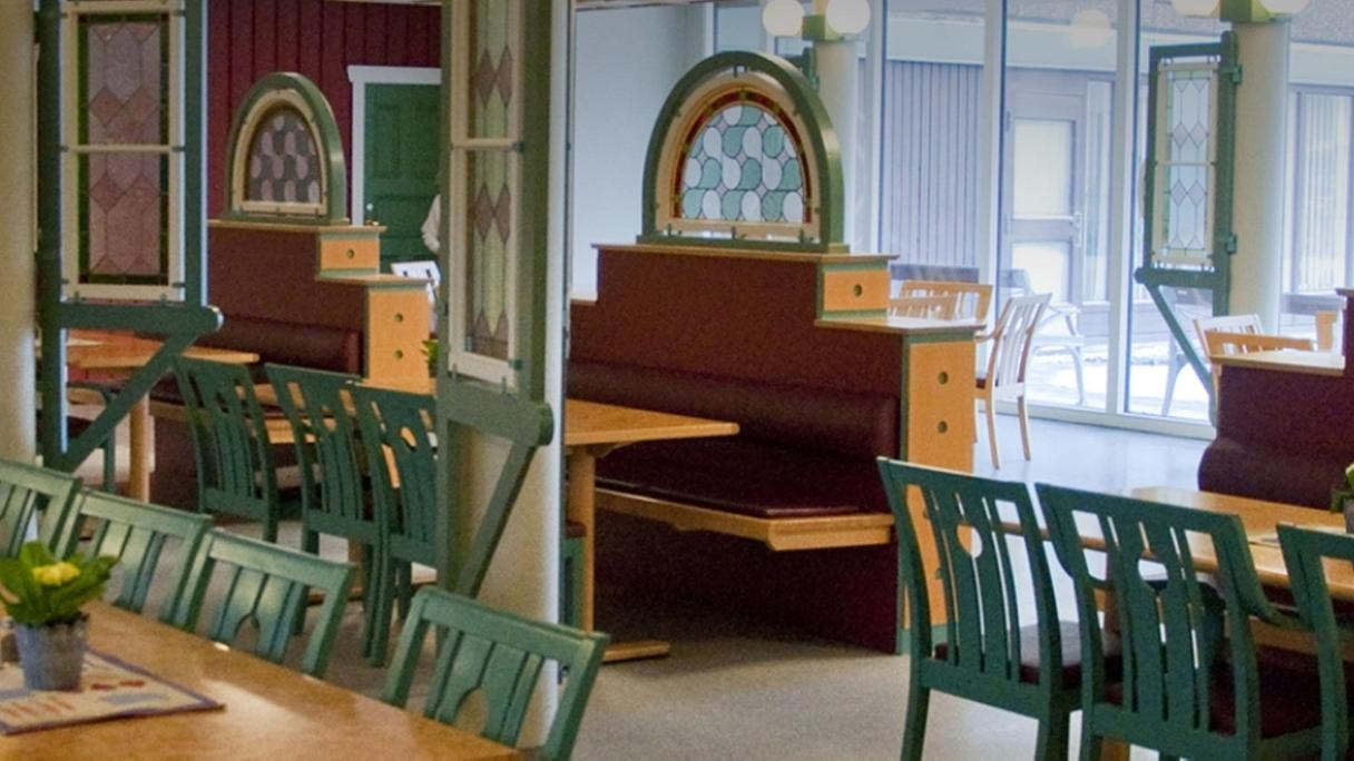 Interiör från matsalen. Furubord med gröna stolar.