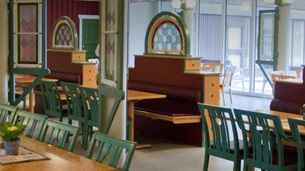 Interiör från matsalen. Furubord med gröna stolar.