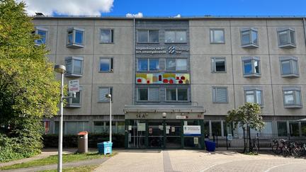 En grå byggnad med konstnärlig utsmyckning ovanför entrén.