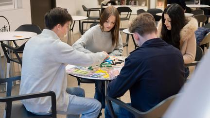 Ungdomar sitter runt ett bord och spelar spel med varandra