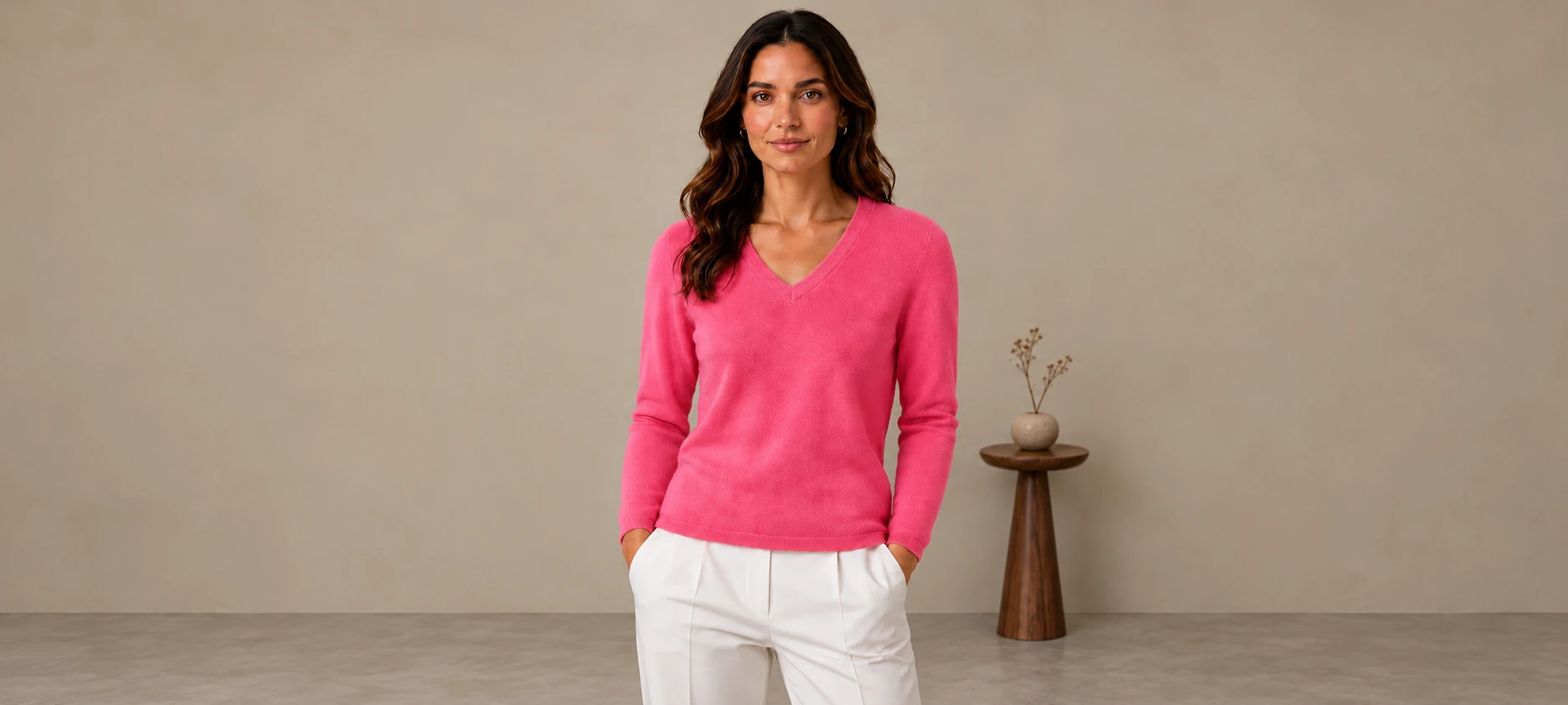 Woman in a pink V-neck beside a small walnut side table and clay vase