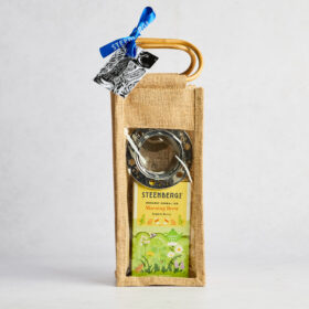 Jute bag with bamboo handles with see through front. Through the front can see stainless steel tea infuser and a box of Steenbergs organic morning brew tea. Ribbon with tag on the handles. Loose Herbal tea gift.