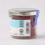 side view of Steenbergs organic pink pepper in jar showing organic logo and B-Corp logo, as well as pink peppercorns and the barcode